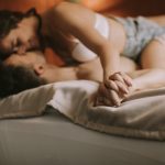 Young adult heterosexual couple lying on bed in bedroom